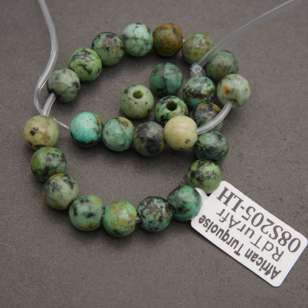 A beaded strand of African turquoise beads with natural green, blue-green, and brown mottled patterns, shown on a gray background with a white product tag.