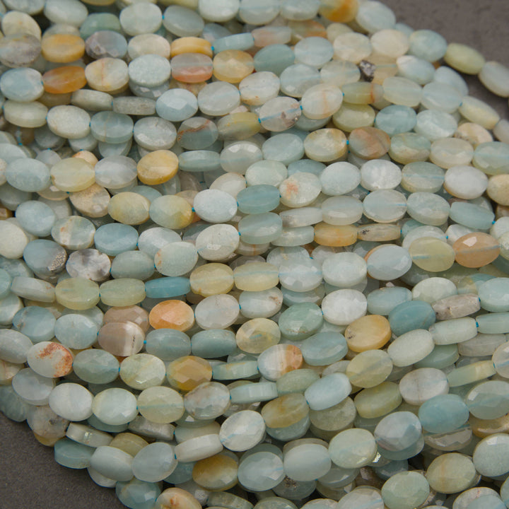 Rows of faceted amazonite oval beads on a gray background in aqua, sky blue, cream and peach