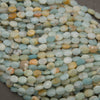 Rows of faceted amazonite oval beads on a gray background in aqua, sky blue, cream and peach