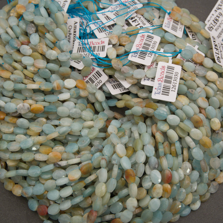 A bundle of faceted amazonite oval bead strands with Tejas Beads tags