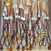 Multiple amber bead necklaces with teardrop and rectangular pendants displayed in a wooden tray. The necklaces feature warm amber, honey, and dark brown beads, with some showing natural inclusions.