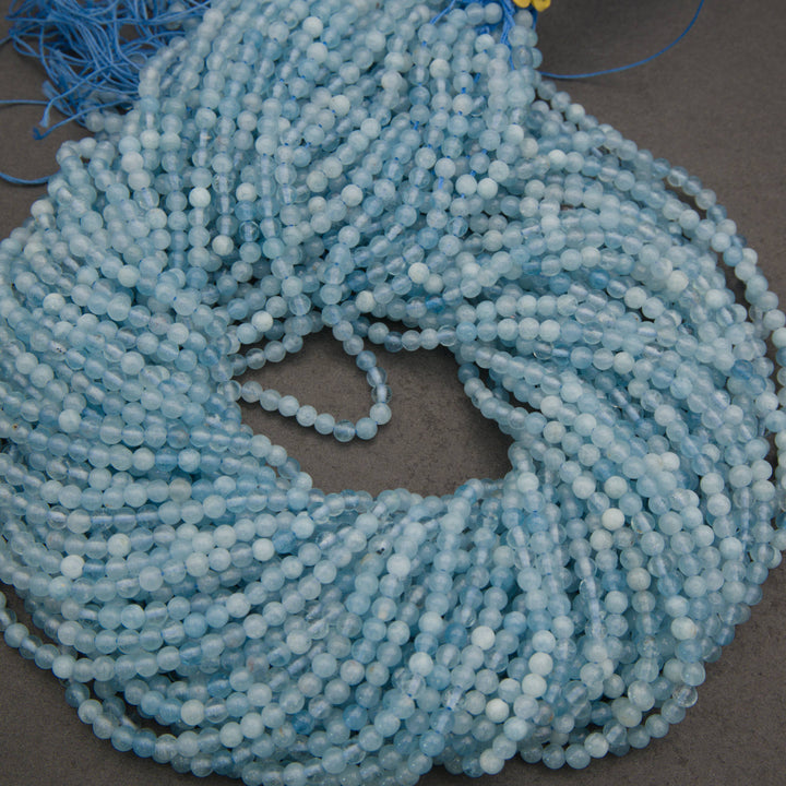 Multiple strands of light blue faceted round beads arranged diagonally on a dark gray surface.