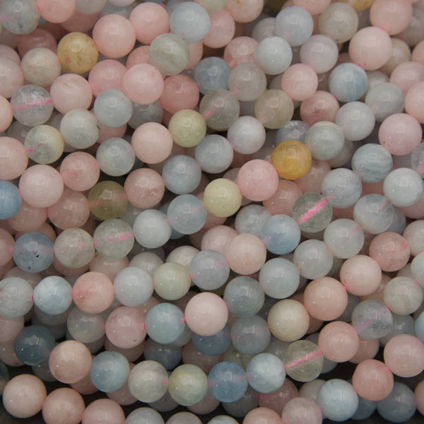 A close-up pile of small round gemstone beads in pastel colors, including pink, blue, pale green, and soft yellow, with some beads showing natural inclusions.
