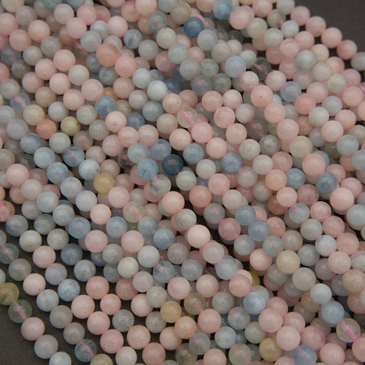 A pile of small, round, matte-finish beads in a pastel mix of pink, blue, gray, and pale green, filling the frame.