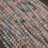 A pile of small, round, matte-finish beads in a pastel mix of pink, blue, gray, and pale green, filling the frame.