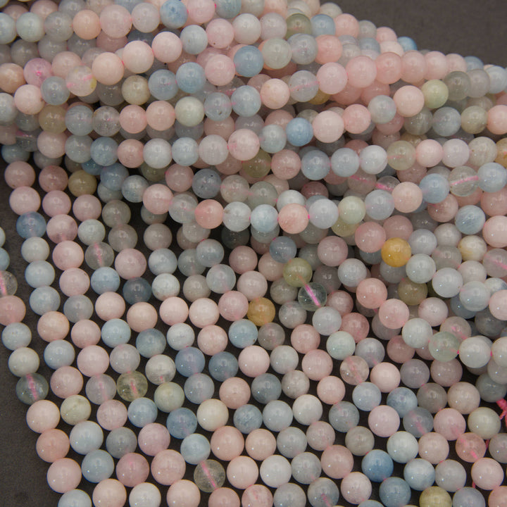 A pile of small round beads in pastel colors, including pink, light blue, pale green, and off-white, with a few translucent yellow beads visible.