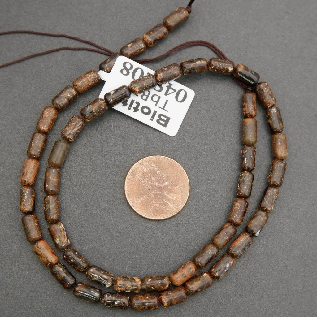 Beaded necklace with a penny for scale on a gray background
