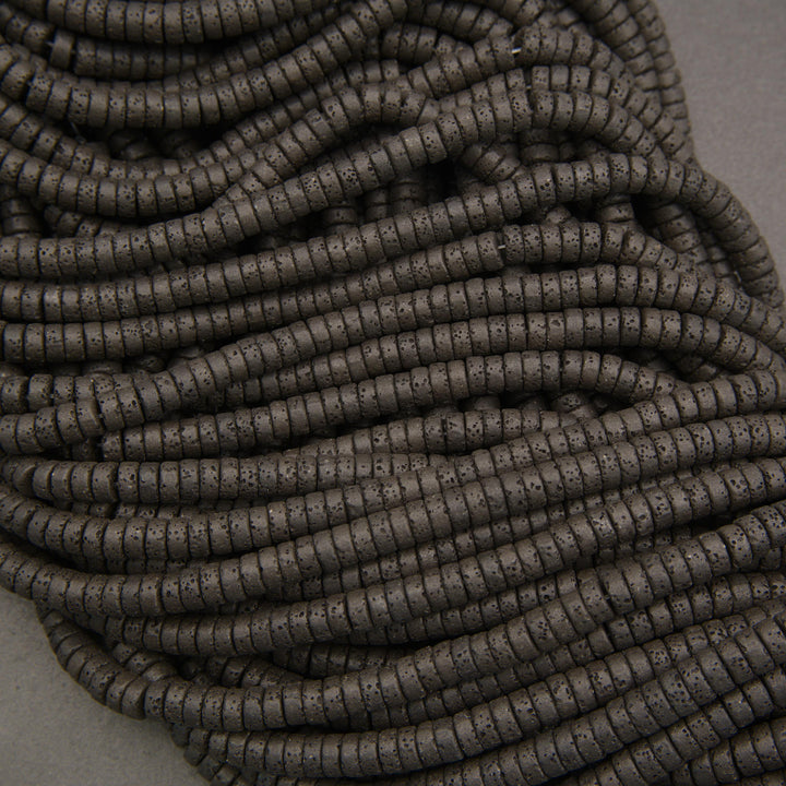 Multiple strands of matte black lava stone heishi beads showcasing natural pores and charcoal-black surfaces.