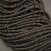 Multiple strands of matte black lava stone heishi beads showcasing natural pores and charcoal-black surfaces.