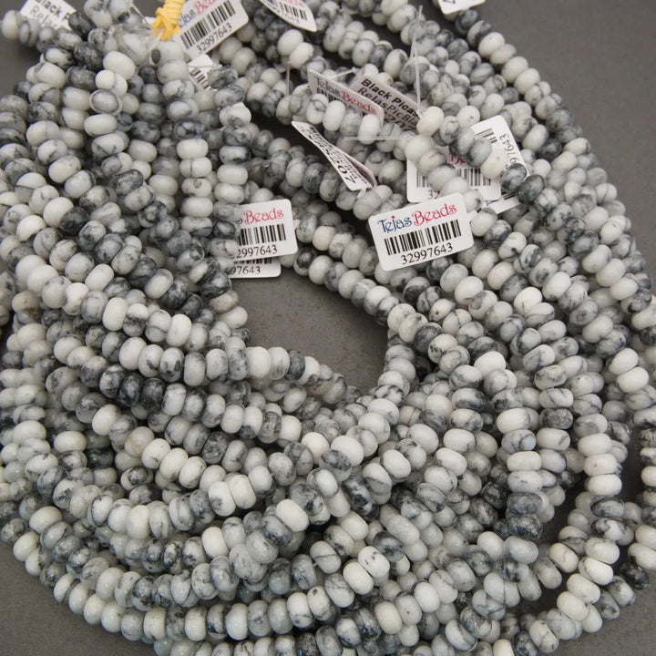 String of gray and white marbled beads with visible brand labels on a gray background