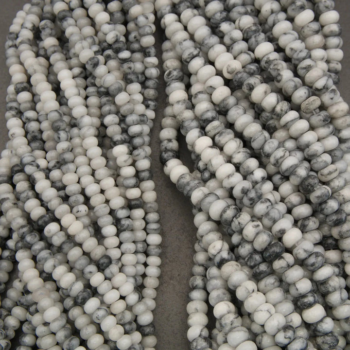 Close-up of two strands of gray and white marbled beads on a dark background