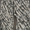 Close-up of two strands of gray and white marbled beads on a dark background