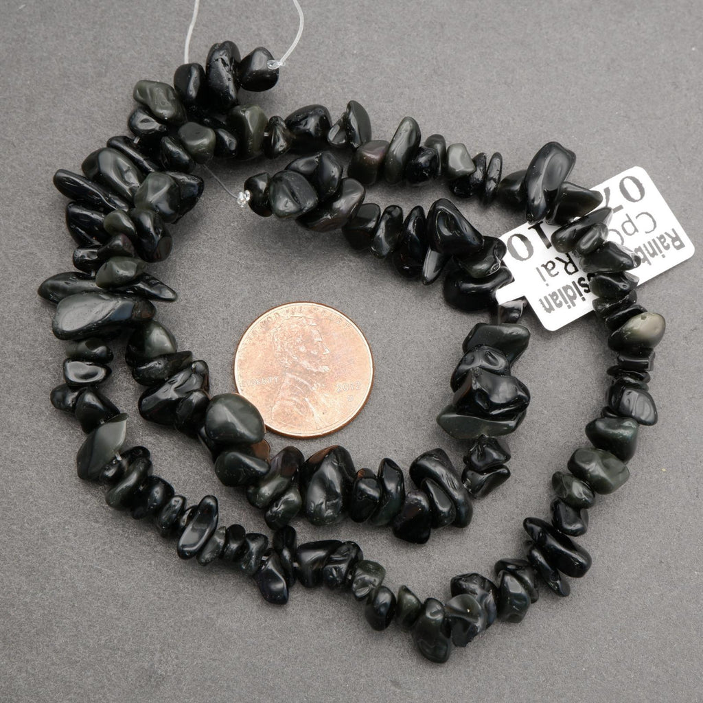 Black stone bead necklace with a penny for scale on a gray background