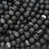 A pile of matte black round beads with natural agate or jasper banding patterns in white, gray, and black.