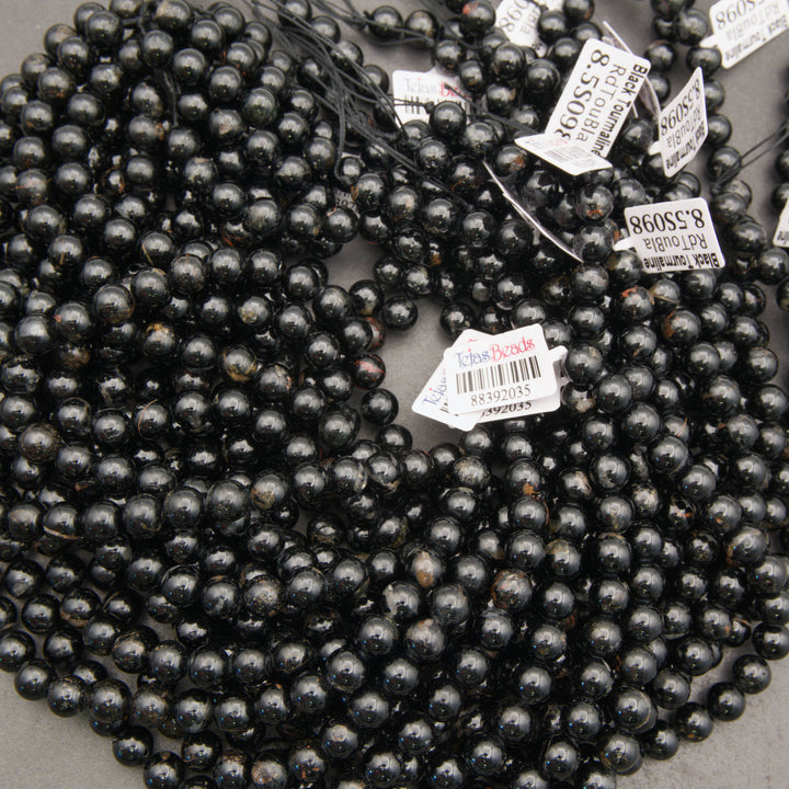 Strands of polished Black Tourmaline beads with occasional mineral inclusions