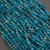 Close-up of multiple strands of faceted turquoise-blue beads on a neutral gray background.