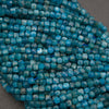 A close-up of strands of faceted turquoise-blue beads on a neutral gray background.