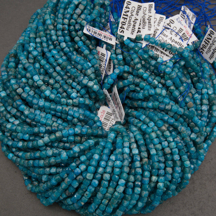 A close-up of strands of faceted turquoise-blue beads on a neutral gray background.
