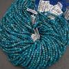 A close-up of strands of faceted turquoise-blue beads on a neutral gray background.