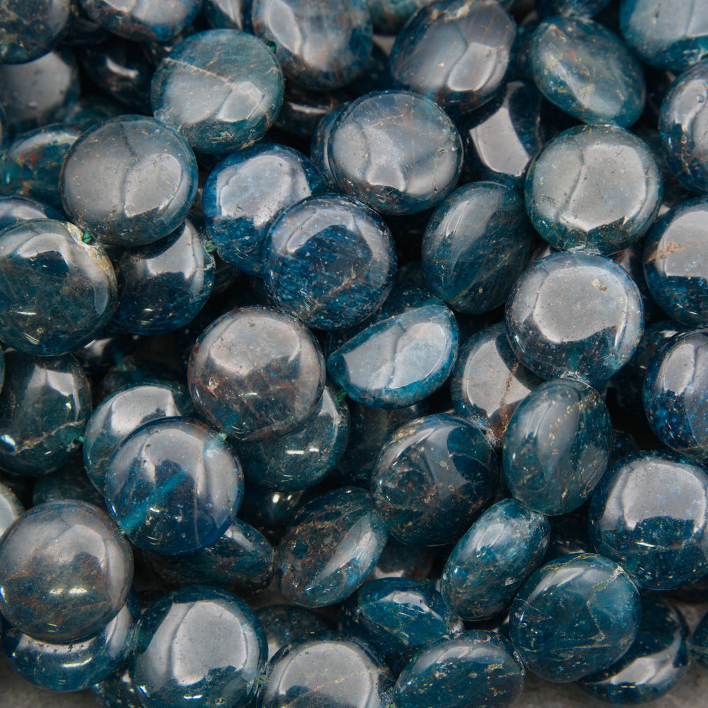 A close-up pile of polished blue teardrop-shaped gemstone beads with a glossy finish and natural inclusions.