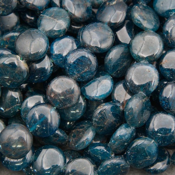A close-up pile of polished blue teardrop-shaped gemstone beads with a glossy finish and natural inclusions.