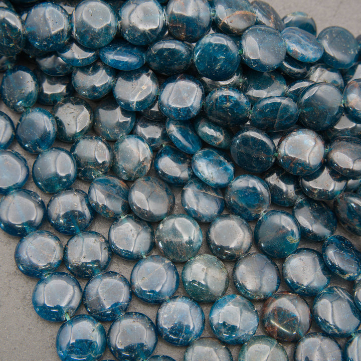 A pile of round, polished blue glass pebbles or beads with a glossy finish, filling the frame against a neutral gray background.