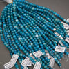 Multiple strands of round turquoise-blue beads with white marbled inclusions, laid out on a gray surface with small white product tags attached.