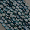 Rows of smooth oval blue apatite beads in deep teal on a gray background