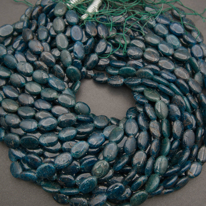 A heap of smooth oval blue apatite bead strands in deep teal
