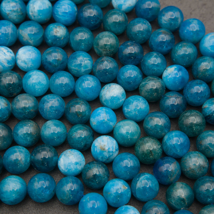 Close-up of rows of smooth round blue apatite beads in teal and bright ocean blue