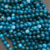 Close-up of a pile of smooth round blue apatite strands in deep teal and ocean blue, some beads with pale sky-blue marbling