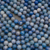 Rows of smooth round blue aventurine beads on a gray background in denim blue and pale blue