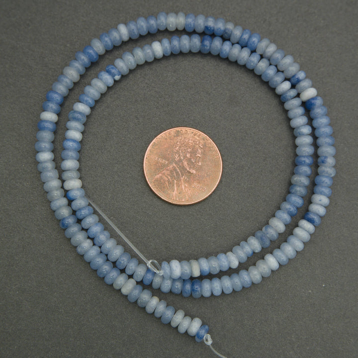 String of blue beads with a penny for scale on a gray background