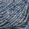A close-up pile of faceted round gemstone beads in shades of light blue, medium blue, and white.