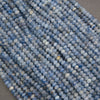Close-up of multiple strands of faceted round beads in shades of light blue, medium blue, and white, arranged diagonally.