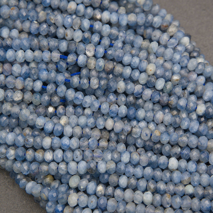 A pile of faceted round beads in a light blue and white marbled pattern, resting on a neutral gray surface.