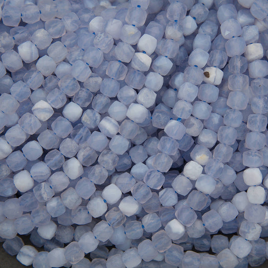 A close-up pile of faceted round beads in a pale icy blue and white marbled pattern.