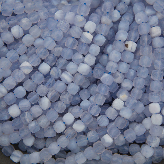 A close-up pile of faceted round beads in a pale icy blue and white marbled pattern.