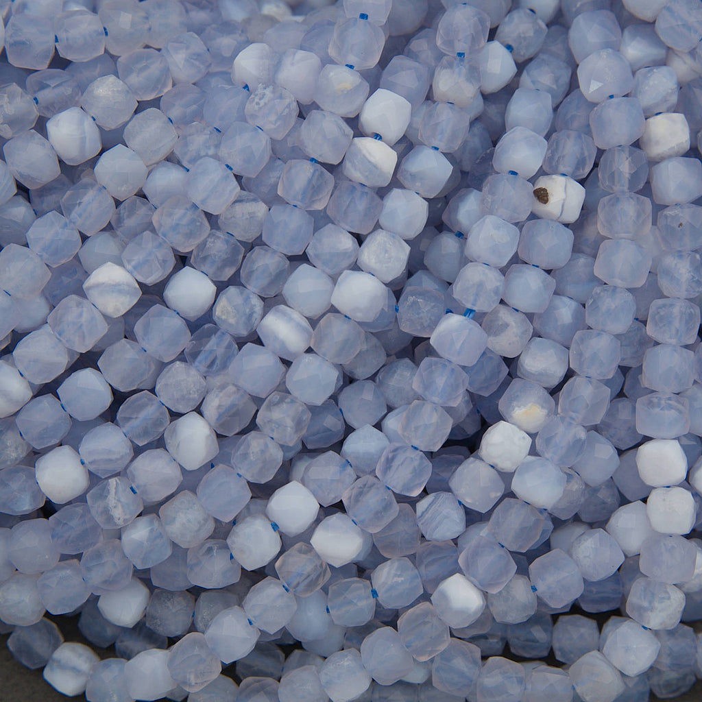 A close-up pile of faceted round beads in a pale icy blue and white marbled pattern.