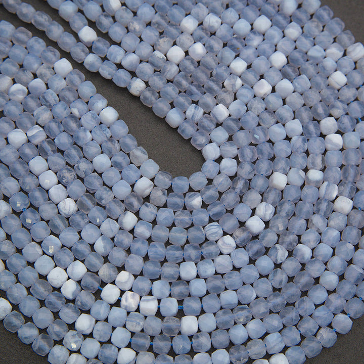 Coiled strands of faceted round beads in a pale icy blue and white marbled pattern, photographed close-up on a dark gray background.