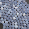 A close-up of faceted oval beads in a mix of pale blue, white, and light gray marbled tones, strung on thin blue cords.