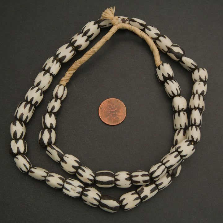 Black and white beaded necklace with a penny for scale on a dark background