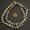 Black and white beaded necklace with a penny for scale on a dark background