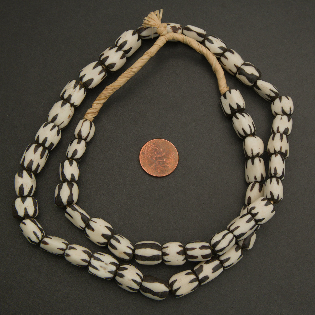 Black and white beaded necklace with a penny for scale on a dark background