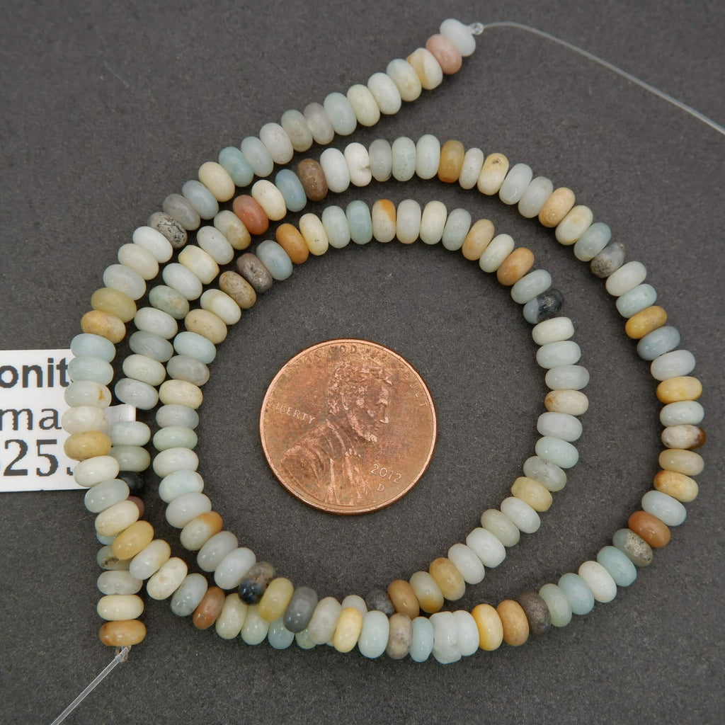 Necklace of multicolored beads with a penny for scale on a gray background