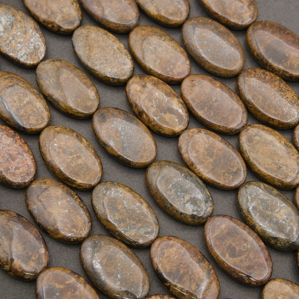 Close-up of smooth oval bronzite beads in rows, golden brown with a metallic bronze sheen