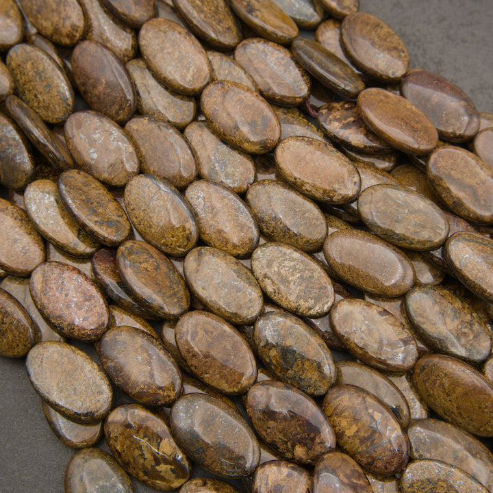 Close-up of strands of smooth oval bronzite beads in bronze, golden brown and chocolate with a fibrous metallic sheen