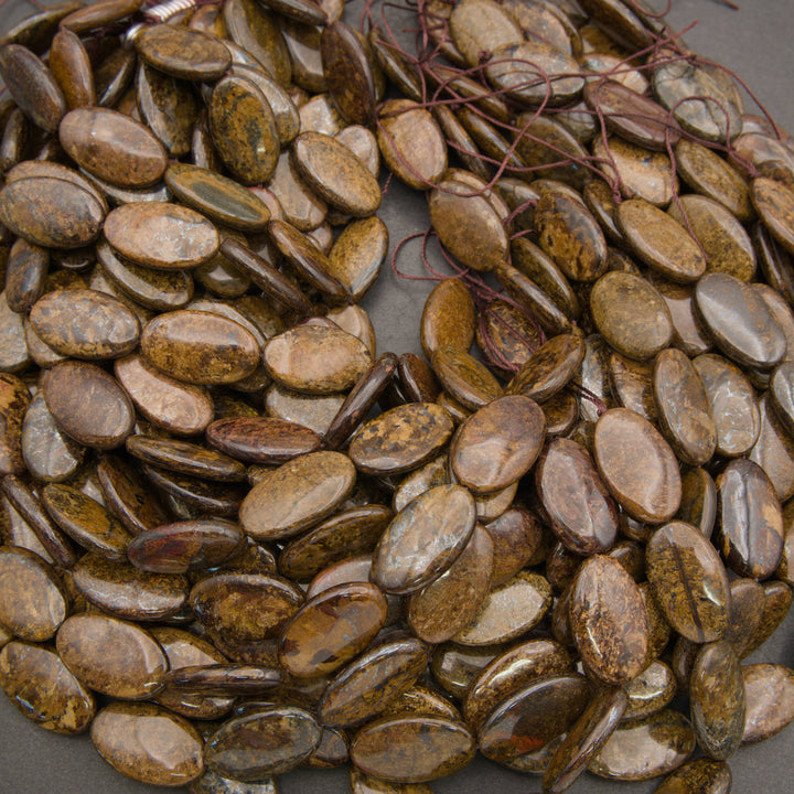 A heap of smooth oval bronzite bead strands in bronze, golden brown and chocolate