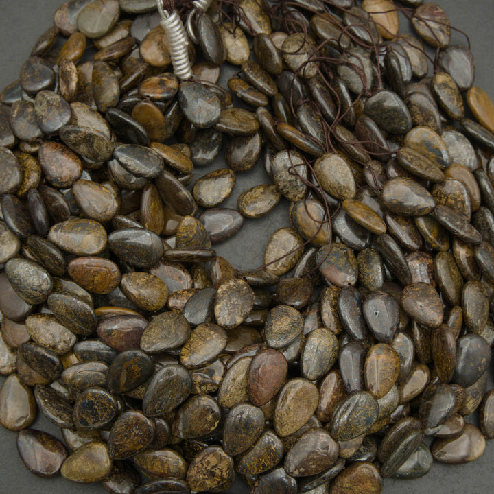 Close-up of a string of brown and gray pebble-like beads on a neutral background