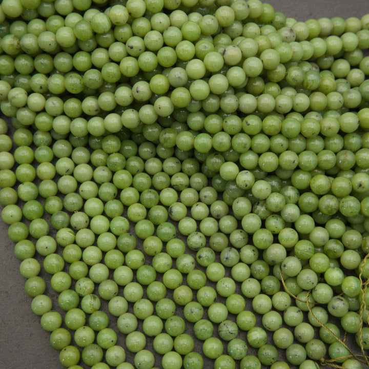 A close-up pile of small, round, light green beads with a glossy finish, filling almost the entire frame.